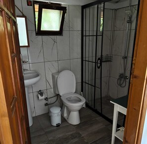 Ein Badezimmer mit Toilette, Waschbecken, Dusche und einem Fenster.