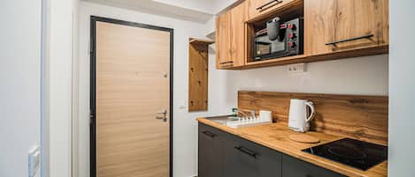 Una cocina moderna con armarios de madera, horno empotrado y una encimera con un hervidor.