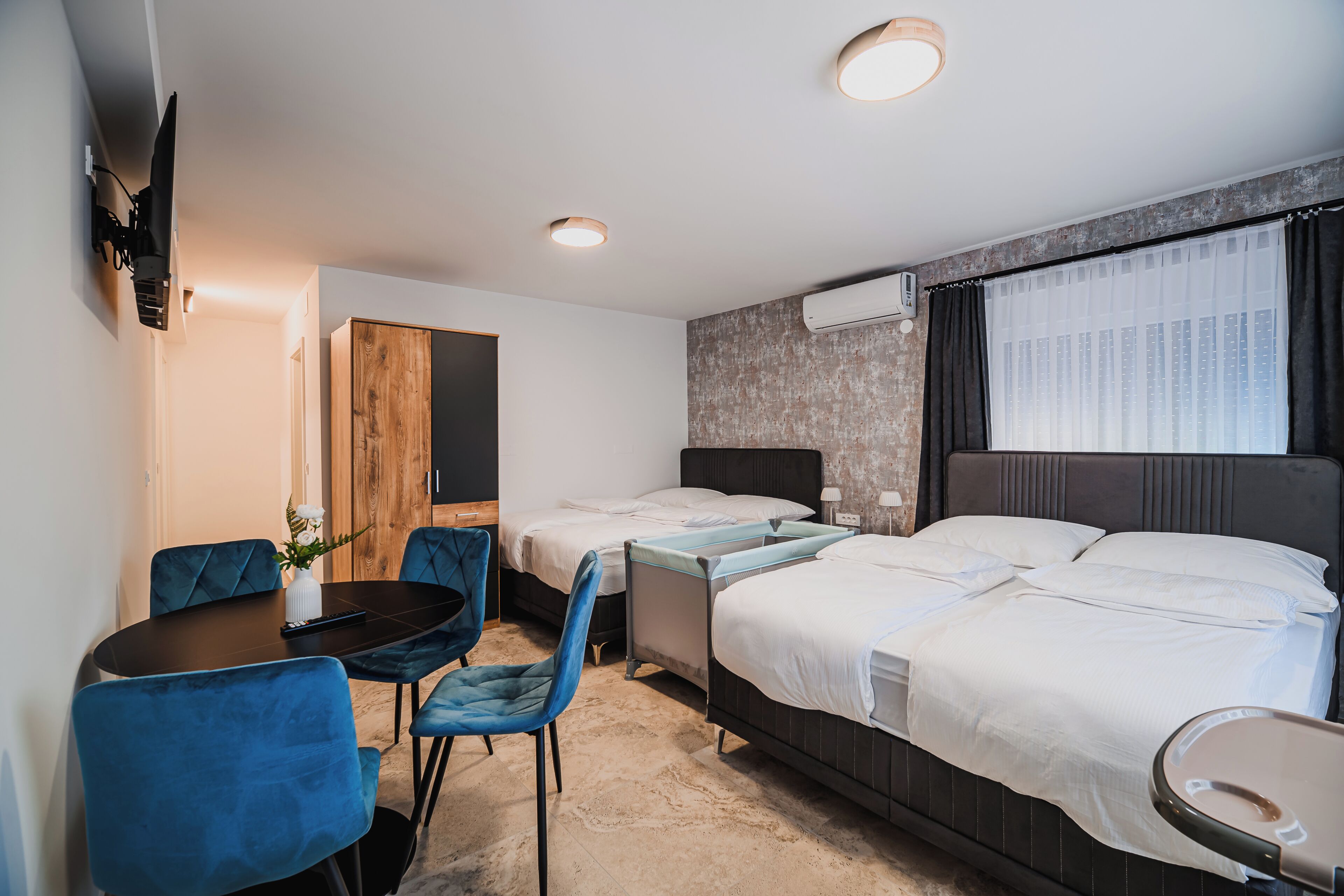 Et hotelværelse med to senge, et skrivebord, stole, et fjernsyn og en aircondition.