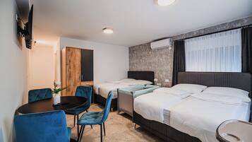 Et hotelværelse med to senge, et skrivebord, stole, et fjernsyn og en aircondition.
