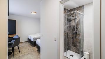 A hotel room with a shower, a bed, a desk, and a chair.