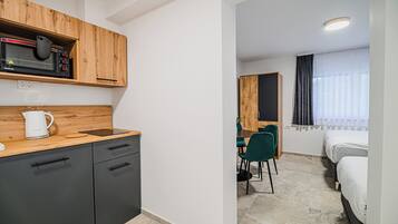 A compact hotel room with a kitchenette, a dining area, and a bed.