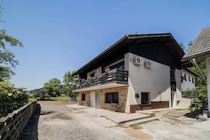 Kaksikerroksinen rakennus, jossa on parveke, ulkotila istumiseen ja kirkas taivas.