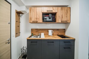 A compact kitchen with wooden cabinets, a built-in microwave, a sink, and a coffee maker. - Apartment House Barsel (Ljubljana)