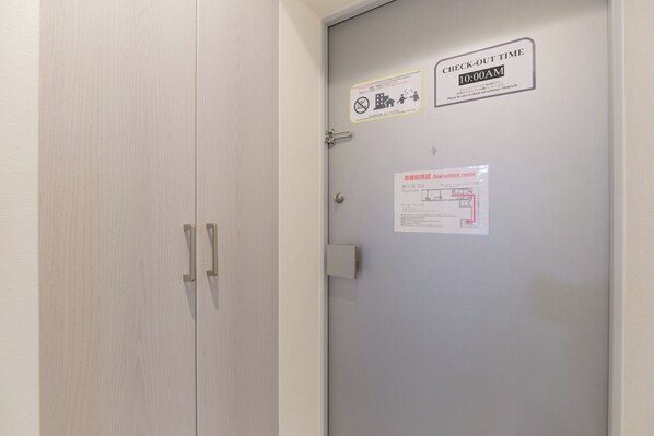 A door with a check-out time sign, a no smoking sign, and a vacuum route map. - Mugenzaka by Tranova 2 (Shibuya)