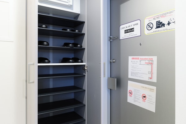 Uma porta com aviso do horário de check-out, mapa das rotas de evacuação e placa de proibição de fumar.