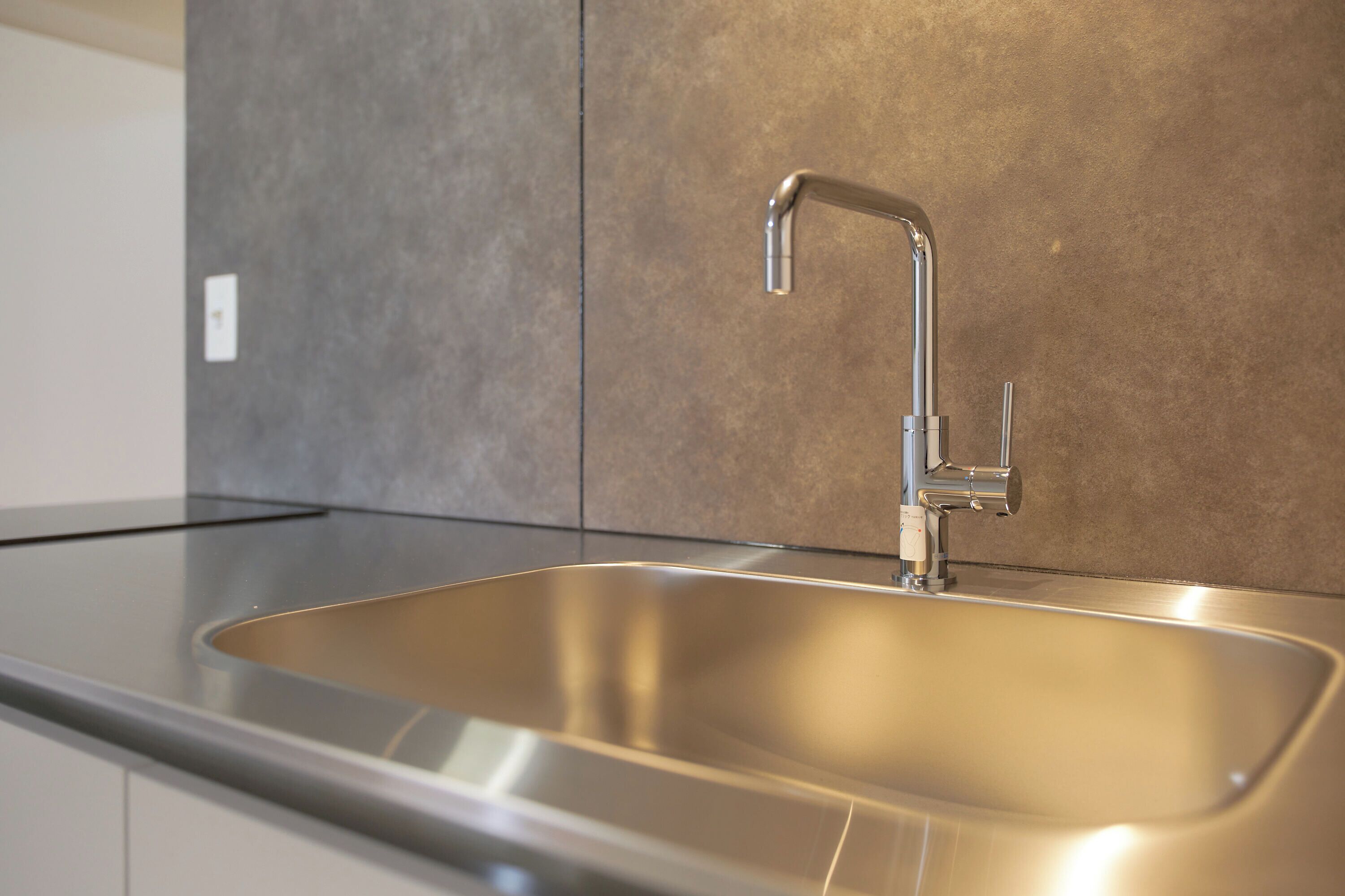 Eine moderne Küche mit Spüle aus Edelstahl, einem Wasserhahn und einer Arbeitsplatte.