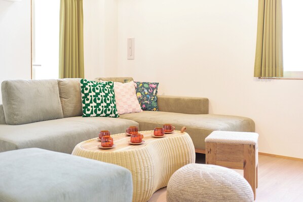 Una sala de estar con sofá, reposapiés y un taburete de madera.