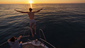 Eine Person auf einem Boot, im Hintergrund ein Sonnenuntergang.