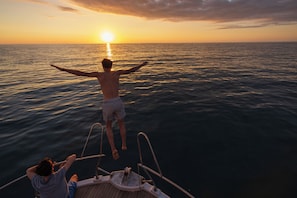 Una persona en un barco con un atardecer de fondo.