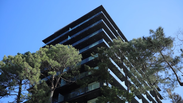 A modern building with multiple floors, surrounded by trees.