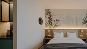 Ein Hotelzimmer mit Bett, Nachttischen, einem Wandbild und einer Kaffeemaschine auf der Ablagefläche.