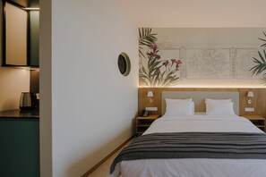 Habitación de hotel con cama, mesitas de noche, una obra de arte en la pared y una cafetera en la encimera.