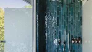 A modern bathroom with a glass door, a shower with a rain showerhead, and a wall-mounted faucet.