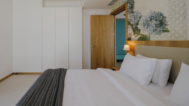 Ein Hotelzimmer mit einem Bett, einer Holztür, einer Wandleuchte und floraler Tapete.