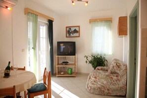 A living room with a television, a dining table with chairs, a sofa, and a potted plant. - Srima Villa Steps from Sandy Beach (Srima)