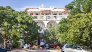 Un edificio con un patio central, un balcón y un coche estacionado en la parte delantera.