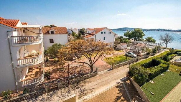 Zona residencial costera con edificios blancos, un balcón y vistas al mar.