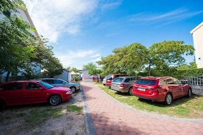 Ein Parkplatz mit mehreren Autos, einem Weg und Bäumen.