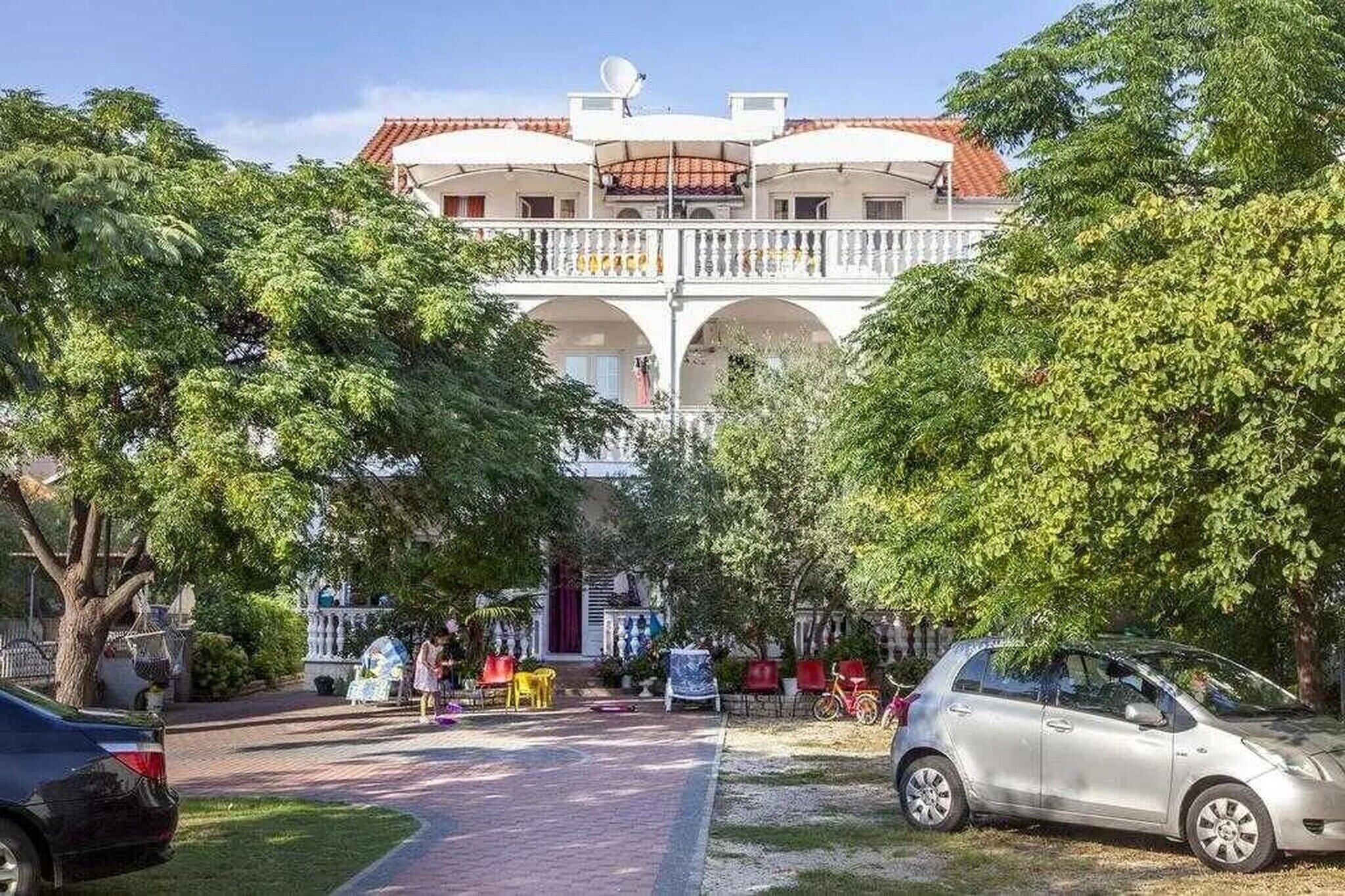 Ein Gebäude mit Innenhof, Balkon und einem geparkten Auto davor.