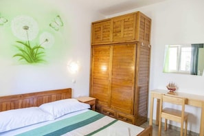 Ein Schlafzimmer mit einem Bett, einem Holzschrank, einem Nachttisch und einem Schreibtisch mit Stuhl.