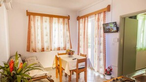 Uma sala de estar acolhedora com um sofá, uma mesa de jantar e uma cozinha com fogão.
