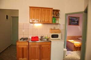 Eine kleine Küche mit Holzausstattung, einer Mikrowelle, einem Spülbecken und einem kleinen Kühlschrank.