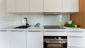 A modern kitchen with white cabinets, a black faucet, a Siemens oven, and a wooden countertop with vegetables. - Conwind 2 - House Conwind. - Apartment 2 (78 m²). In Keitum for up to 4 people (Sylt)