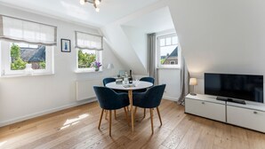 A modern apartment with a dining area, a TV, and large windows. - Conwind 2 - House Conwind. - Apartment 2 (78 m²). In Keitum for up to 4 people (Sylt)