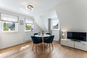 Eine moderne Wohnung mit Essbereich, Fernseher und großen Fenstern.
