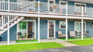 Een tweelaags huis met een overdekte veranda, buiten zitplaatsen en een trap die naar de bovenverdieping leidt.