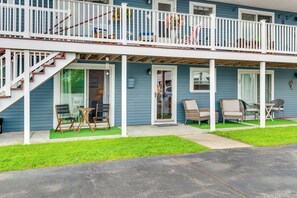 Ein zweistöckiges Haus mit überdachter Veranda, Sitzgelegenheiten im Freien und einer Treppe zum oberen Stockwerk.