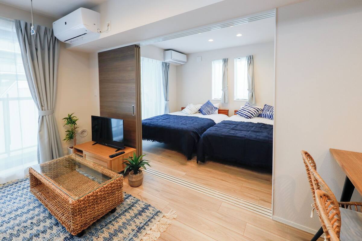A modern hotel room with a large bed, a TV, a wooden desk, and a wicker chair.
