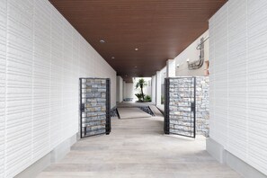 Um corredor com paredes de tijolo branco, teto de madeira e parede de pedra no final.