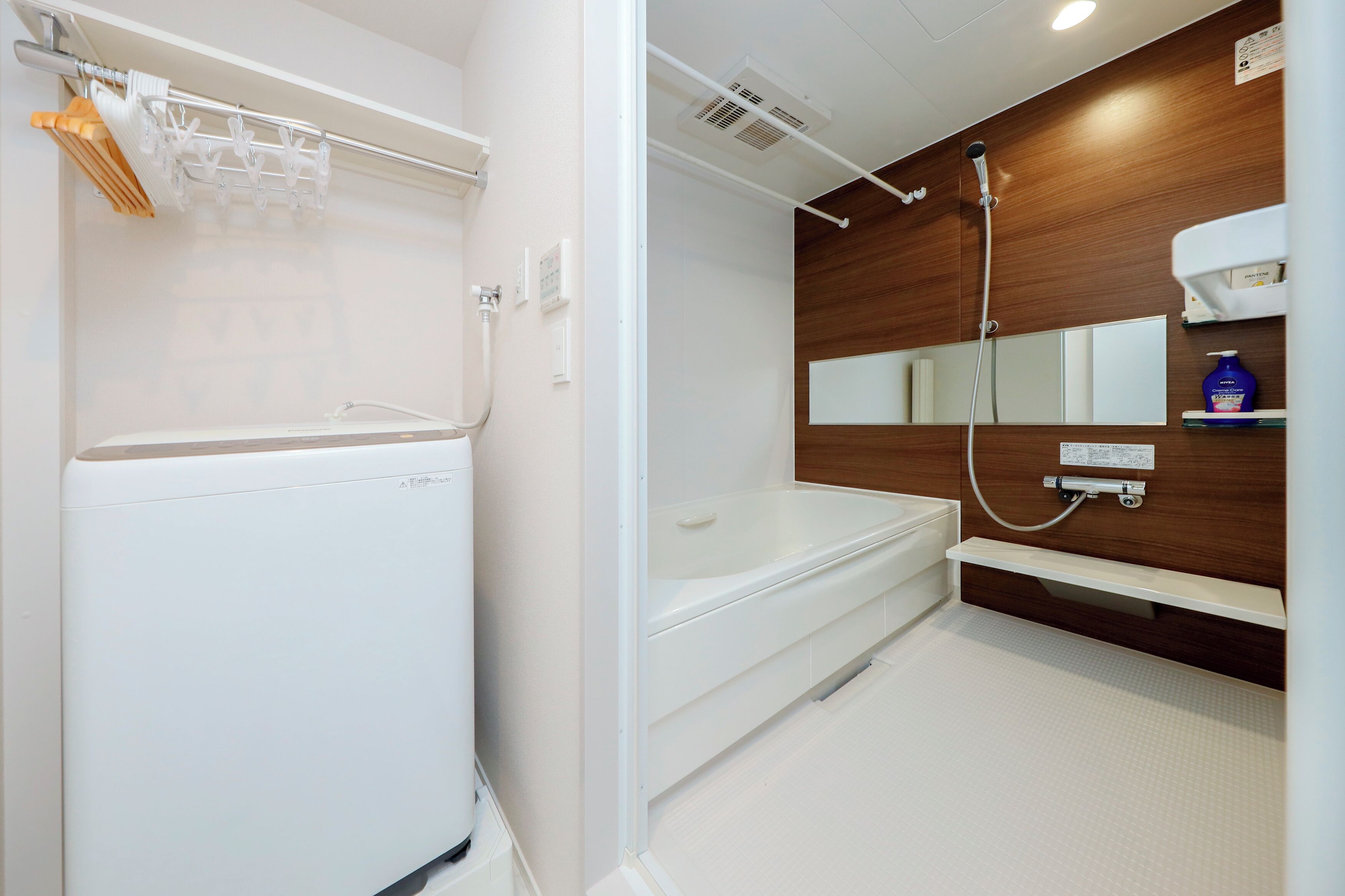 A modern bathroom with a white bathtub, a shower, a towel rack, and a mirror.