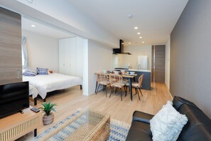 Una sala de estar moderna con cama, televisor, sofá y un comedor con sillas y mesa.