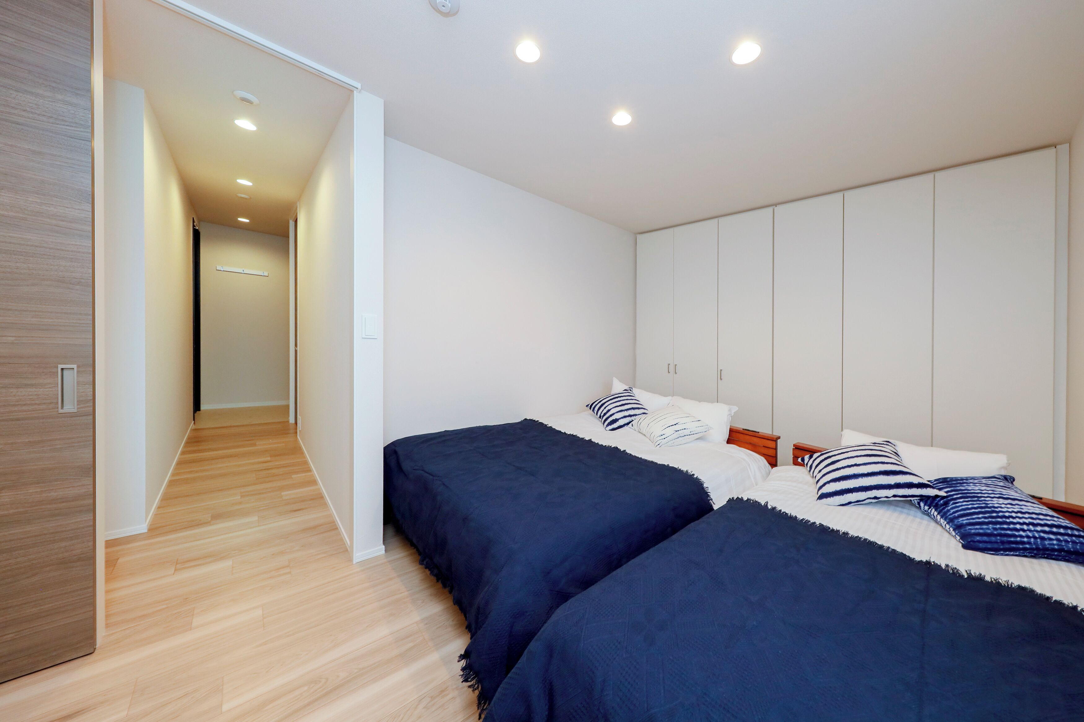 Un dormitorio moderno con dos camas, un armario y un pasillo que conduce a otra habitación.