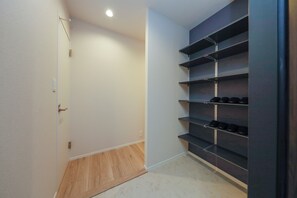 Un couloir avec une porte, un plancher en bois et une étagère métallique adossée au mur.