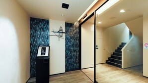 Un interior moderno con una recepción, una obra de arte en la pared y una escalera que sube a un nivel superior.
