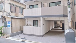 Un edificio residencial de varios pisos con balcones, fachada de tejas y una entrada visible.
