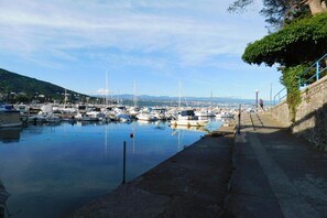 A marina with boats docked, a stone pathway, and a hilly landscape in the background. - Sea View Apt with Terrace Kitchen (Opatija)
