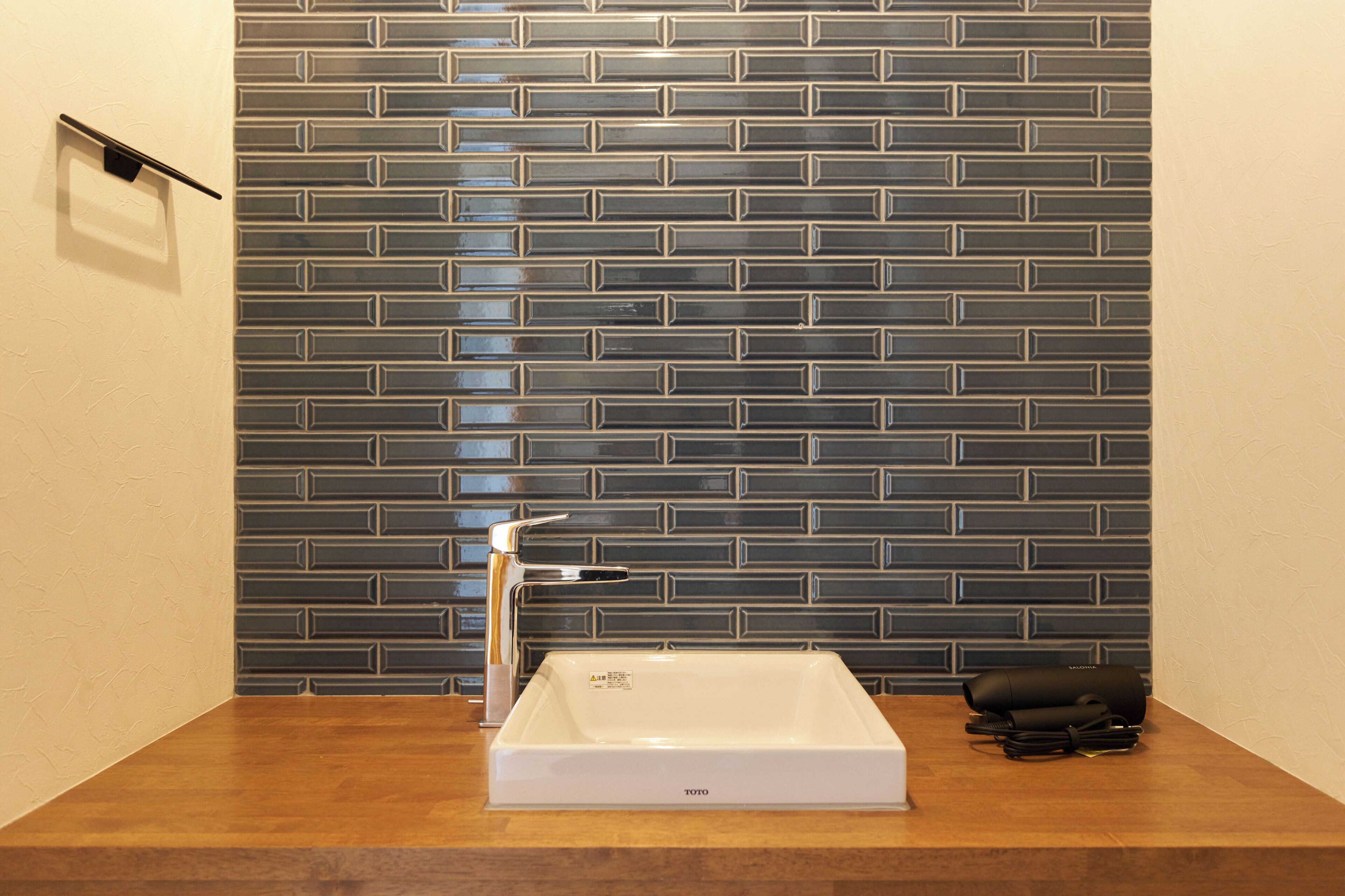 A bathroom with a white sink, a modern faucet, and a tiled backsplash.