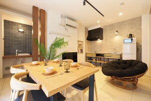 A modern kitchen with a dining area, including a wooden table, chairs, and a unique black chair.