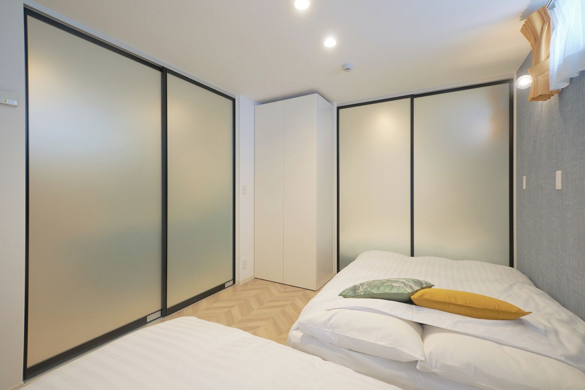 A bedroom with two beds, a wardrobe, and a ceiling light.