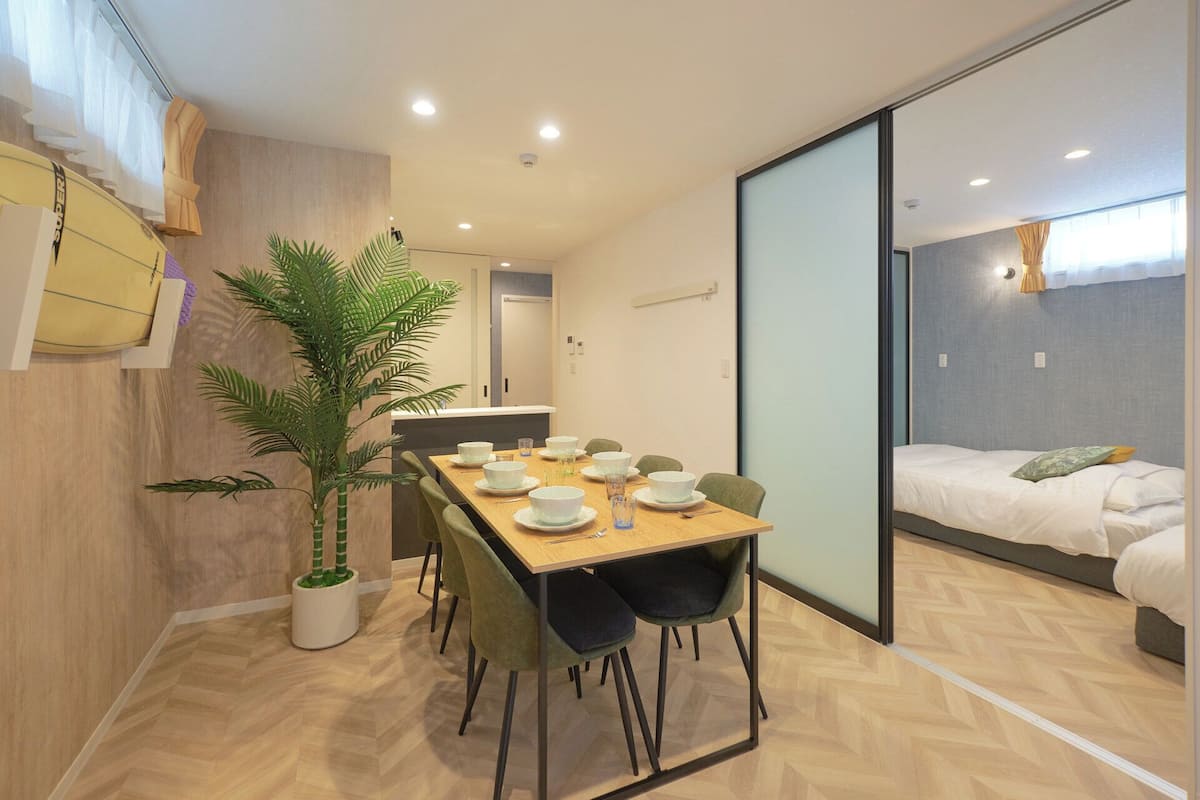 A modern hotel room with a dining area, a bed, and a large potted plant.