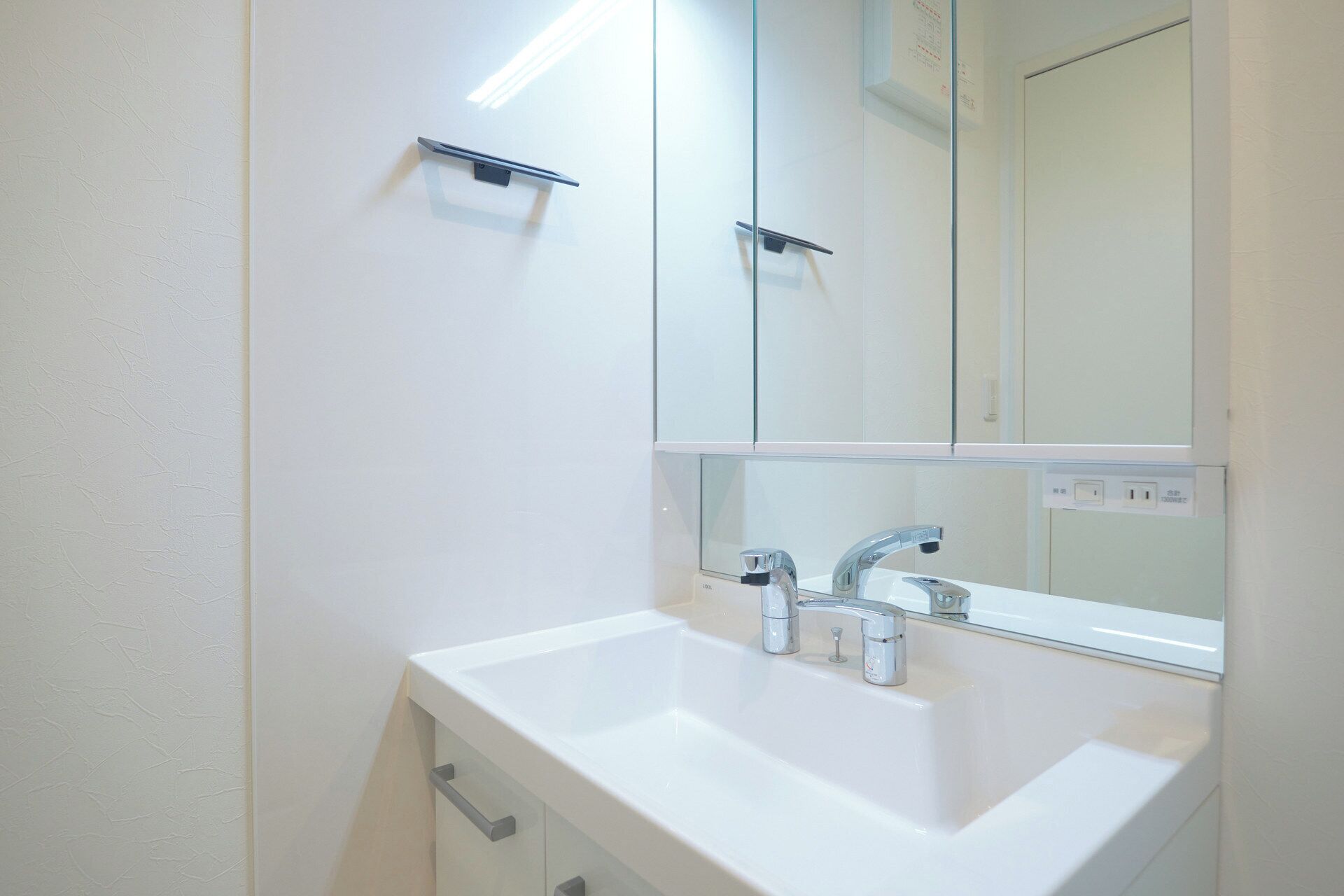 A bathroom with a white sink, two faucets, and a mirror above it.