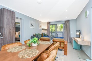 Ein modernes Wohnzimmer mit Esstisch, einer Couch und einer kleinen Küchenzeile.