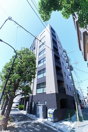 Ein mehrstöckiges Gebäude mit moderner Architektur, das eine Reihe von Balkonen und einen gut sichtbaren Eingang im Erdgeschoss zeigt.