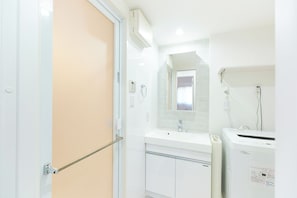 A bathroom with a white sink, mirror, and a white washing machine. - Creare Togoshi Ginza by Tranova  2 (Tokyo)