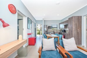 Ein modernes Wohnzimmer mit einer Couch, einem Esstisch und einer Küche im Hintergrund.